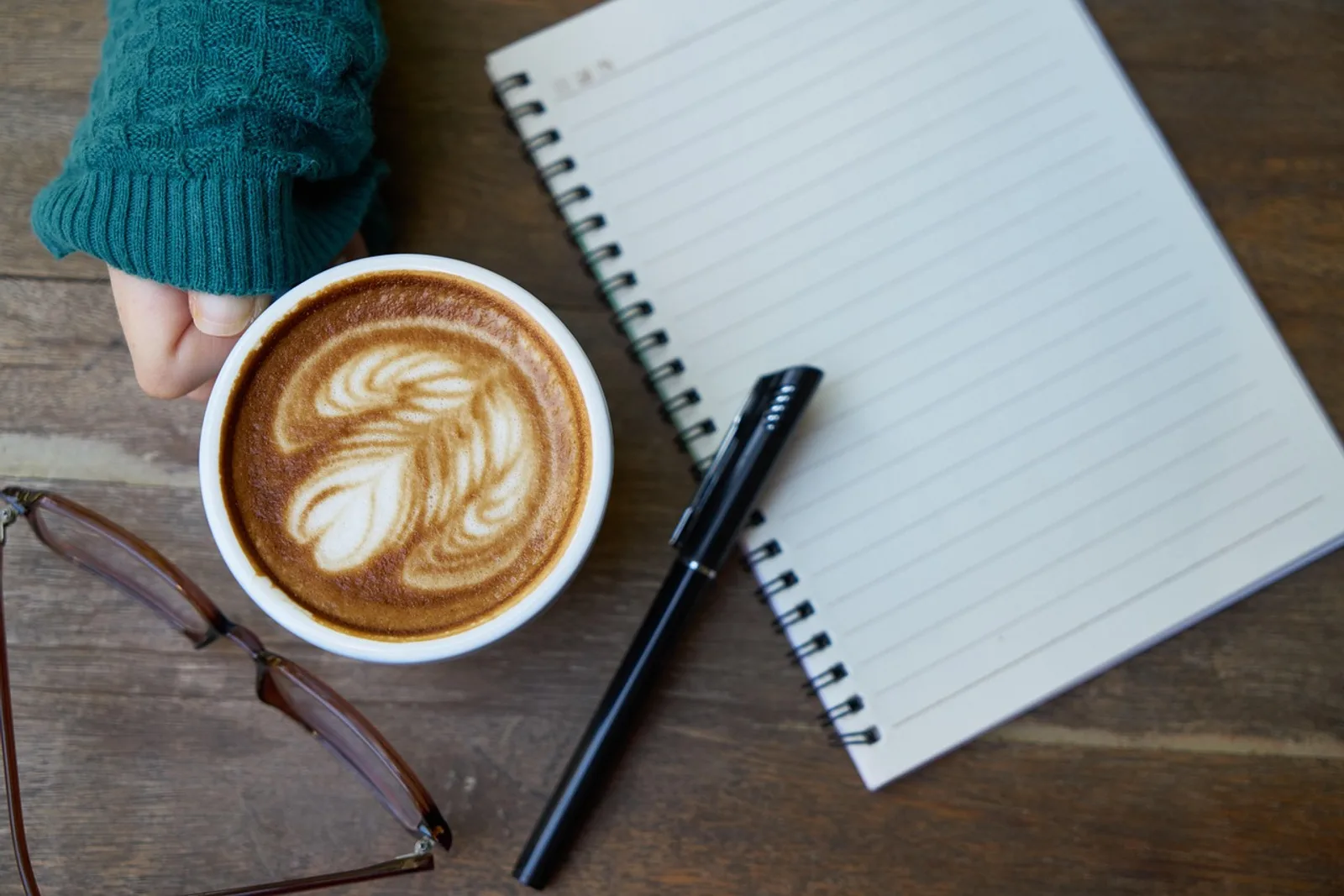 Woman sitting thoughtfully at a kitchen table with a pen, scared to negotiate salary before the big talk