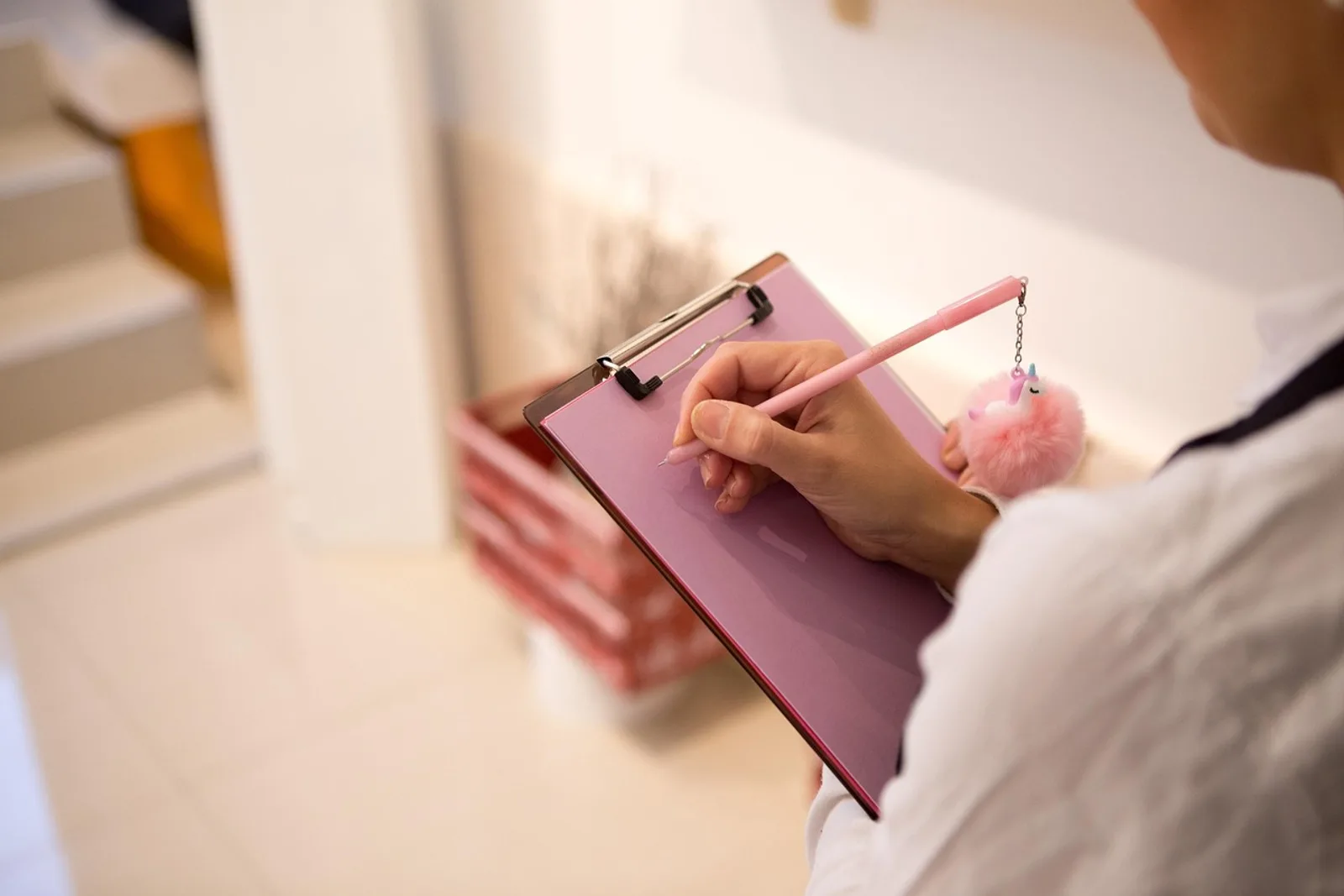Woman ticking off a paper habit tracker on her kitchen wall in the morning, showing how to use a habit tracker