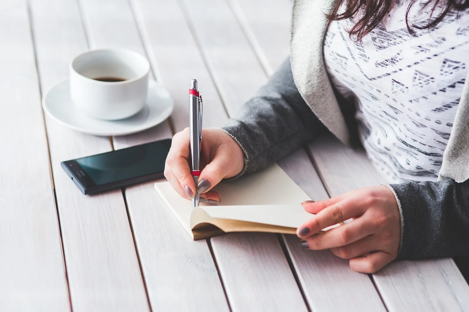 Woman hesitating at her desk before signing a contract, a typical moment of self sabotage in business