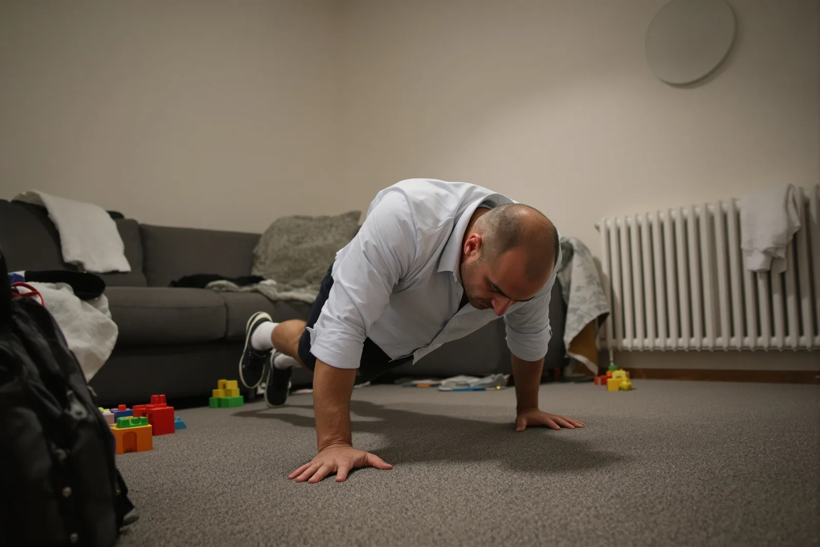 Man in a shirt doing one push-up on a living room rug, showing how to start small habits in everyday life