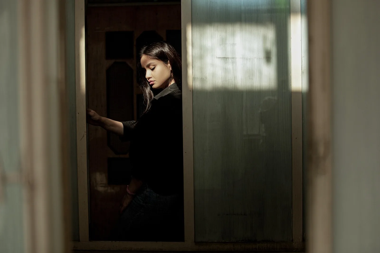 Woman pausing in a doorway and looking thoughtfully at the floor, learning how to stay calm under pressure