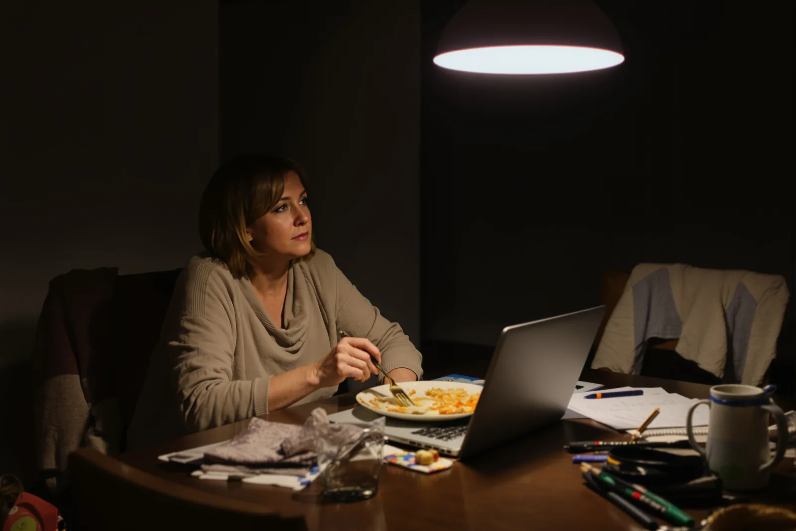 Woman eating dinner alone at her laptop, staring into space: how to stop thinking about work after work