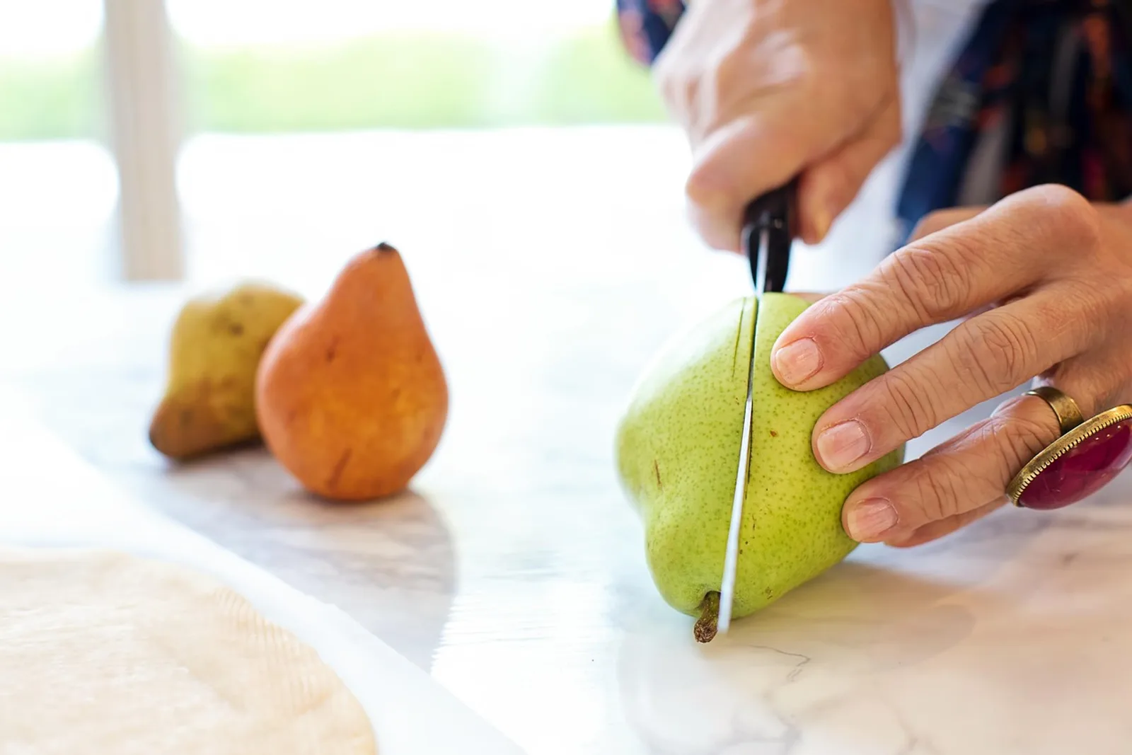 Woman cutting fruit in the kitchen in the morning: small, fixed elements make a realistic morning routine stable