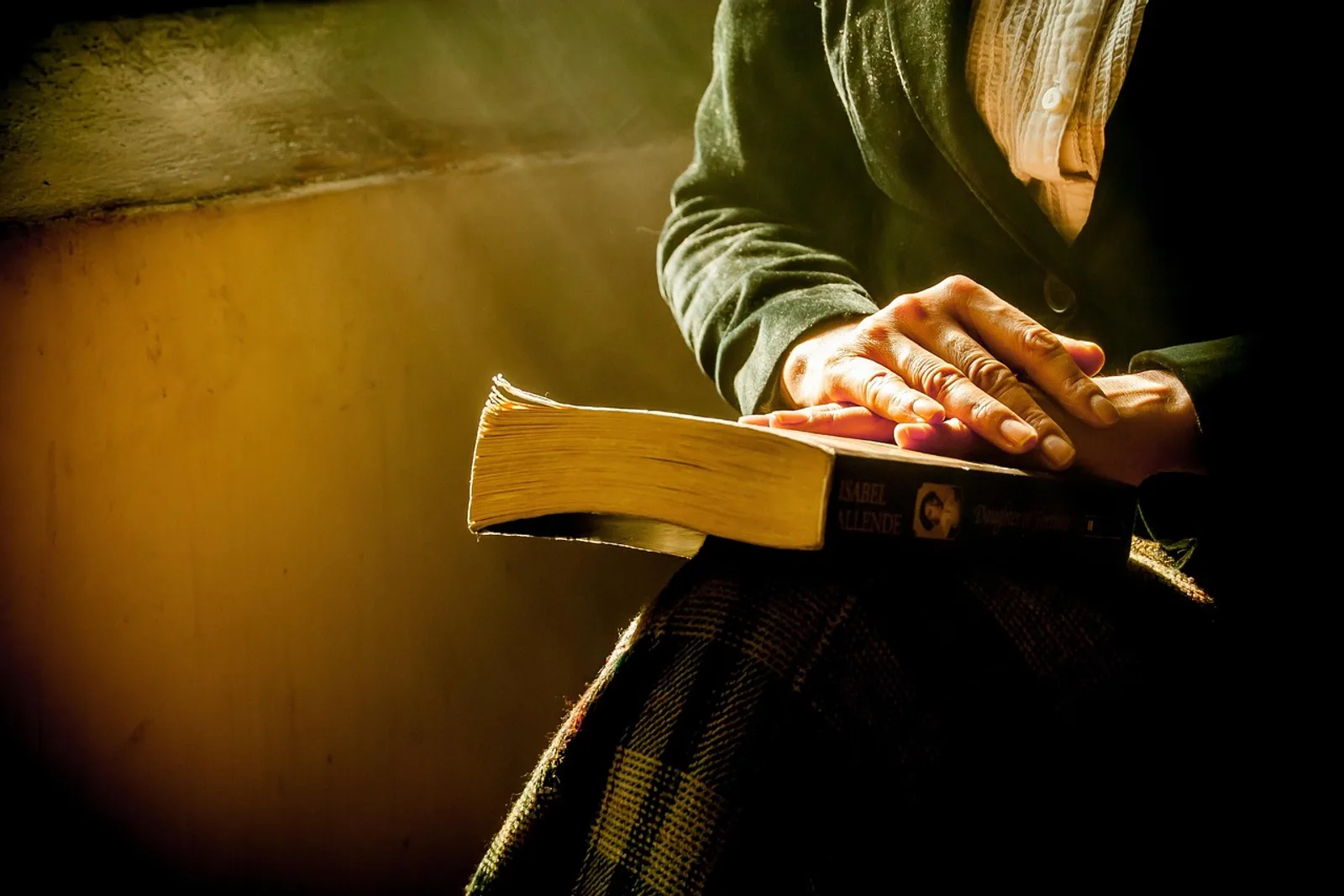 Hands resting on a book in the lap of a seated person, a quiet moment before practising self hypnosis step by step