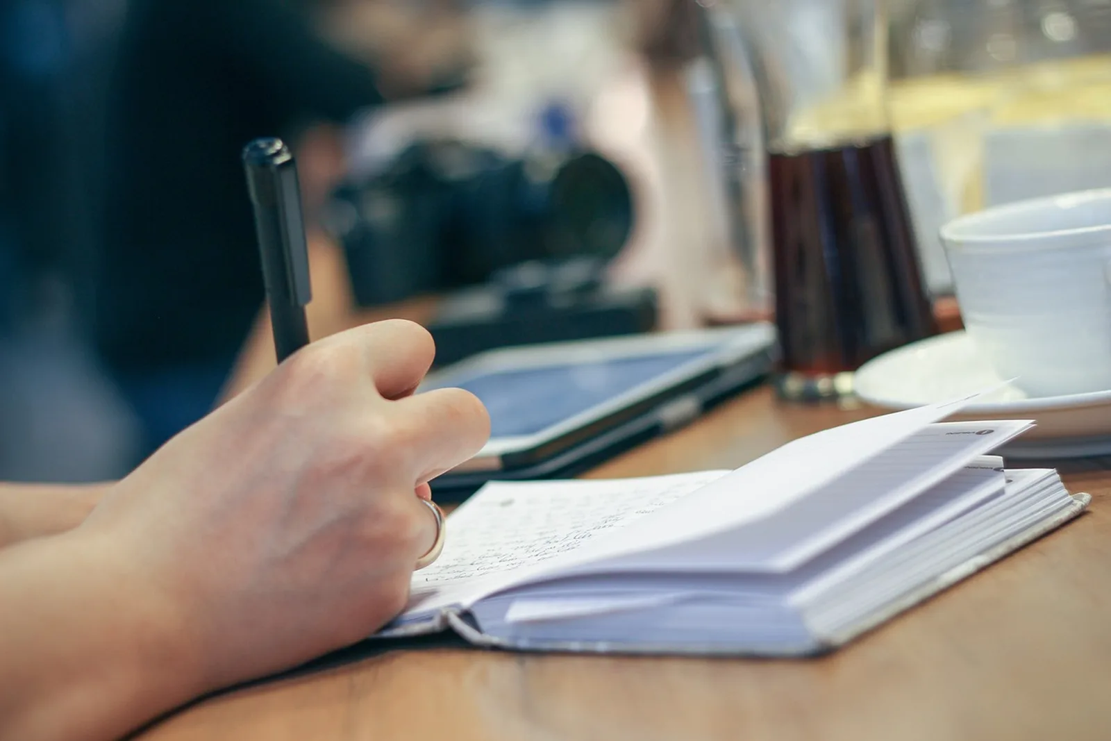 Hand führt im Café ein kleines Ausweich-Protokoll im Notizbuch. Der erste Schritt, um die eigenen Aufschieberitis-Ursachen zu erkennen