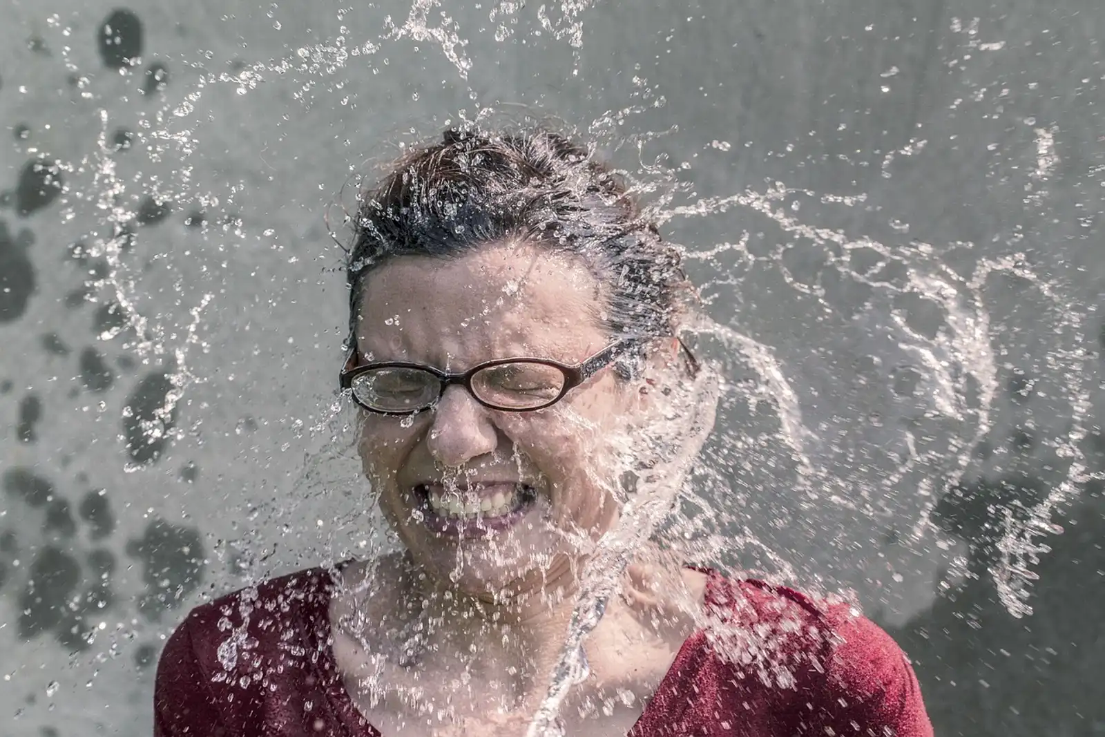 Innere Unruhe loswerden: Frau mit geschlossenen Augen, kaltes Wasser spritzt ihr ins Gesicht